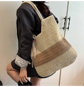Detail of a large woven straw tote bag featuring brown gradient and colorful bead charm
