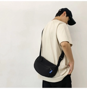 Side view of a black crescent nylon crossbody bag worn by a model for a casual look