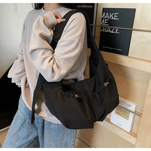 Détail du sac croissant en nylon noir avec fronces latérales et boucle de sangle réglable