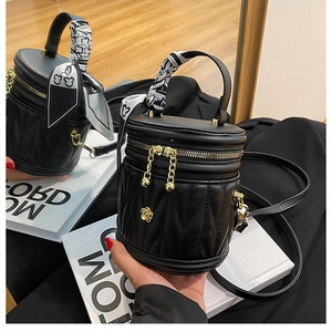 Detail of black quilted bucket bag with silk scarf handle and golden flower hardware