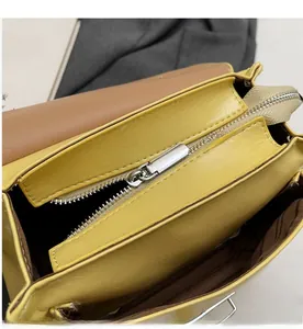 Close-up of the smooth metal zipper and brown striped lining of the yellow handbag