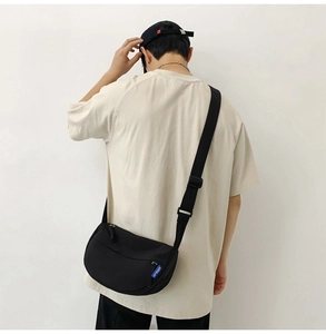 Detail of black nylon crossbody bag with adjustable wide strap and blue brand label