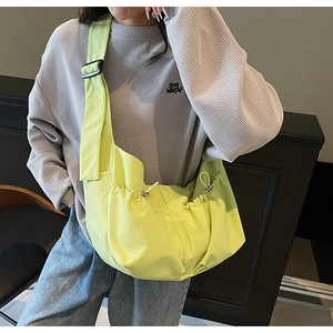 Détail du sac bandoulière en nylon vert clair avec poche latérale à cordon et boucle