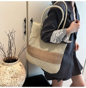 Detail of large woven straw tote bag with dual-tone color blocking and long shoulder straps