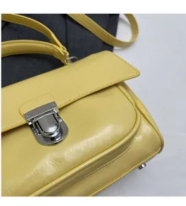 Detailed close-up of bright yellow textured leather bag with silver metal buckle closure