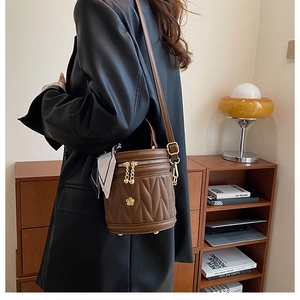 Detail view of a brown quilted bucket bag with gold hardware and stylish silk scarf detail