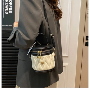 Quilted bucket bag detail showing contrast panels and floral gold emblem on shoulder strap