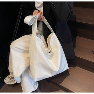 Detailed view of a large white minimalist tote bag with soft faux leather texture and drape