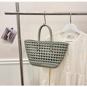 Detail of sage green hollow woven silicone basket bag on a stainless steel hanger