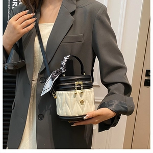 Detail of quilted bucket bag with camellia pendant and silk scarf wrapped on handle