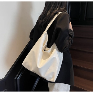 Minimalist cream tote bag styled on dark blazer for high-fashion commute aesthetic