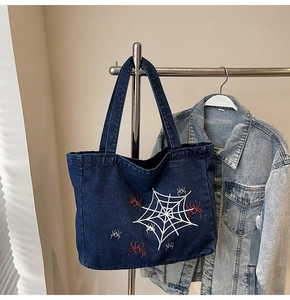 Detail der Spinnen- und Netzstickerei auf einer dunkelblauen Jeans-Einkaufstasche