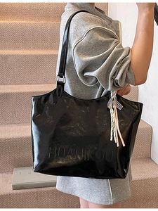 Glossy black PU leather tote bag with embossed logo and decorative braided pendant