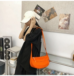 Detail shot of bright orange nylon crossbody bag featuring an adjustable shoulder strap