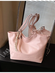 Pink faux leather large capacity tote bag with woven rope charm on a mirror surface