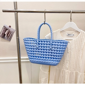 Detail of sky blue hollow out woven tote bag hanging in a minimalist boutique setting