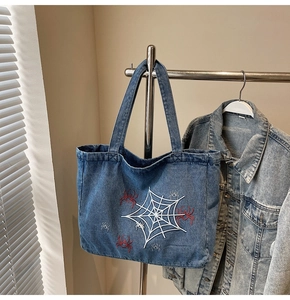 Detail der blauen Denim-Tragetasche mit Spinnennetz-Print und roter Spinne