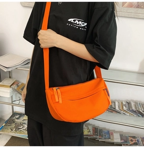 Detail of bright orange crescent crossbody bag made of water-resistant nylon material