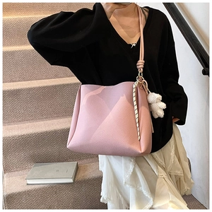Sac seau rose en cuir grainé avec breloque ourson porté à l'épaule par un mannequin