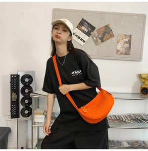 Detail of a bright orange crescent crossbody bag with adjustable wide strap for daily use