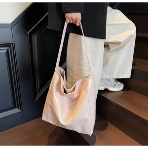 Detailed view of light pink large capacity tote bag with glossy finish on stairs