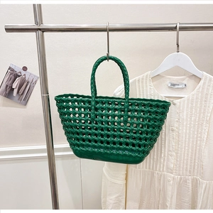 Detailed close-up of a vibrant green woven silicone tote bag featuring hollow grid texture