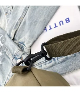Detail of durable black matte metal swivel hook and green canvas strap on women's chest bag