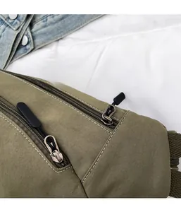 Detail of dual zipper structure and contrast stitching on olive green canvas chest bag