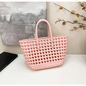 Close-up of a light pink hollow woven jelly tote bag with a modern mesh structure