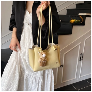 Detail of light yellow lychee pattern tote bag with cute bear charm and thin shoulder straps