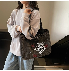 Detail der Schultertasche aus gewaschenem Denim mit Spinnennetz-Stickerei im Streetwear-Stil