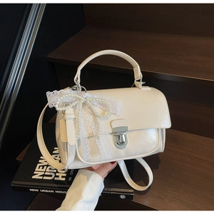 Detail of cream white PU leather bag with lace bow, pearl chain and silver lock