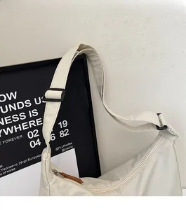 Detail of adjustable black buckle and brown zipper pull on minimalist off-white canvas bag