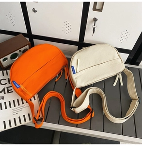Detail view of orange and cream canvas crescent bags with wide adjustable straps