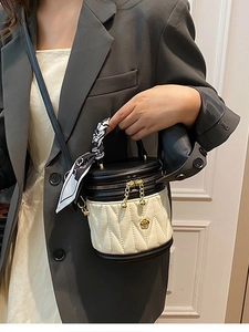 Quilted cylinder bucket bag in cream and black with silk scarf handle and gold floral charm