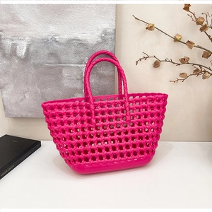 Detail of magenta silicone woven basket bag with hollow mesh design and round handles