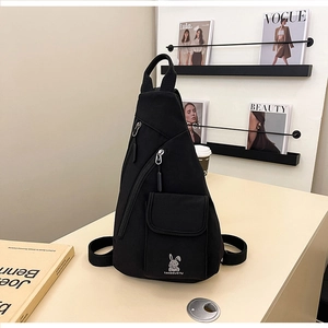 Detail einer schwarzen Brusttasche mit seitlichen Reißverschlüssen und süßem Hasenlogo
