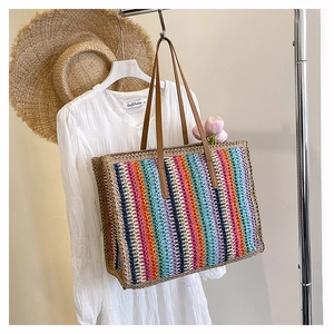 Close-up of rainbow striped woven tote bag with brown faux leather shoulder straps