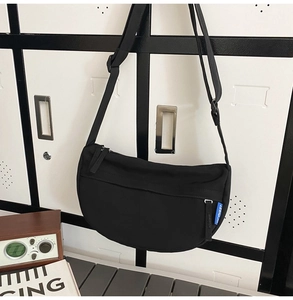 Detail of minimalist black nylon crescent crossbody bag with woven adjustable strap