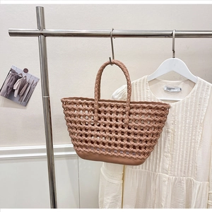 Detail of a brown woven silicone hollow tote bag with round handles and mesh design