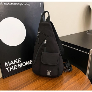 Detail der schwarzen Brusttasche aus Nylon mit Hasenprint und Reißverschlüssen auf Holztisch