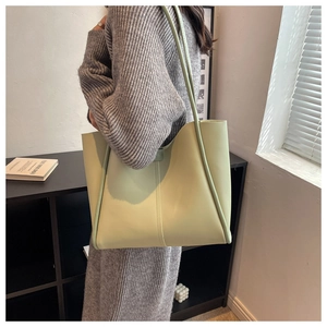 Chic pistachio green leather tote bag shown on a wooden shelf in a cozy home setting