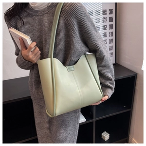 Detailed close-up of light green PU leather tote bag worn with grey knit dress