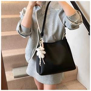 Détail du sac seau en cuir grainé noir avec un pendentif ours en peluche blanc mignon