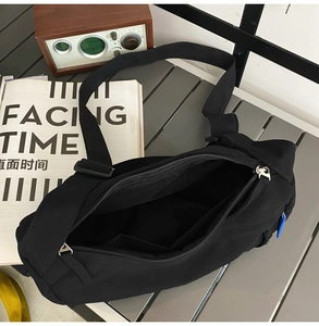 Interior detail of black nylon crossbody bag showing inner pockets and silver zipper