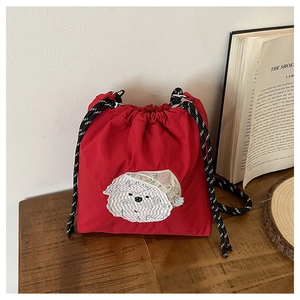 Detailansicht der roten Beuteltasche mit weißer Welpen-Stickerei auf einem Holztisch