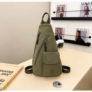 Nahaufnahme der armee-grünen Canvas-Brusttasche mit Hasen-Logo auf einem modernen Schreibtisch