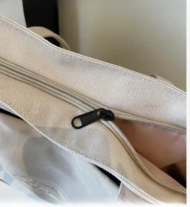 Détail de la fermeture éclair argentée et du curseur noir sur un sac cabas en toile