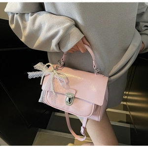 Detail of pink glossy crossbody bag with silver clasp and lace pearl bow ornament