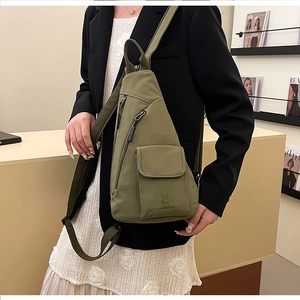 Detail einer olivgrünen Canvas-Brusttasche mit mehreren Reißverschlussfächern und Logo